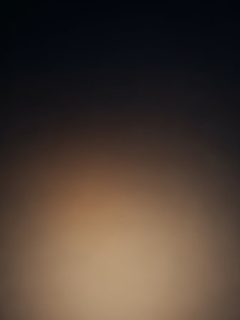 A soft, blurred gradient background that smoothly transitions from a deep dark navy blue at the to a warm light brown at the bottom.の素材