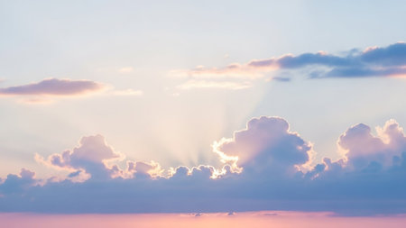 Soft pastel pink and blue clouds are illuminated by gentle sun rays breaking through, creating a serene and tranquil sky atmosphere.の素材