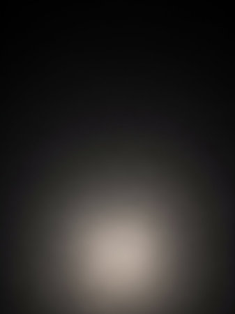 An abstract background with a soft, diffused light emanating from the bottom center, fading into a smooth dark gray and black gradient.の素材