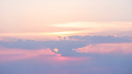 A serene pastel sky soft pink and lavender clouds illuminated by gentle golden light from a sunrise or sunset.の素材