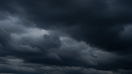 Dark, heavy storm clouds fill the sky, creating a moody and foreboding atmosphere with deep gray and blue tones.の素材