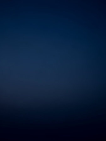 A deep, dark navy blue gradient smoothly transitions to black at the bottom, offering a and minimalist background for digital applications.の素材