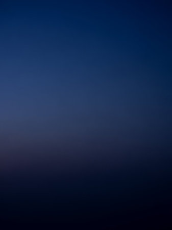 A smooth, deep gradient transitions from dark navy blue to indigo and then to a very dark almost black hue, creating a subtle abstract background.の素材