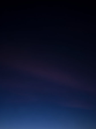 A deep gradient of navy blue and dark purple fills the frame, with faint horizontal light streaks adding subtle texture and depth to the atmospheric sky.の素材