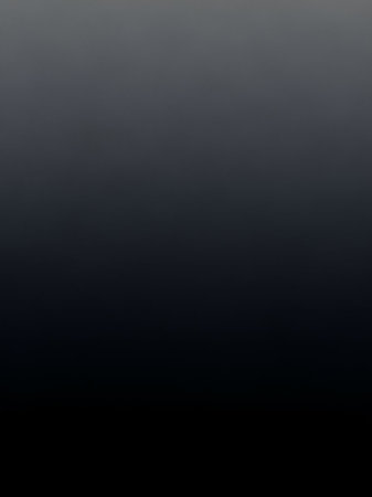 A smooth gradient transitioning from dark gray to black with subtle lighter gray at the creates a minimalist and abstract background.の素材