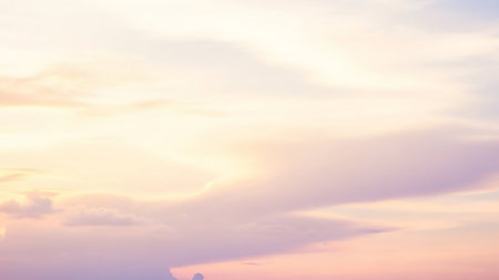A soft gradient of pastel pink, purple, and yellow hues fills the sky, with wispy clouds creating a gentle, atmospheric haze.の素材