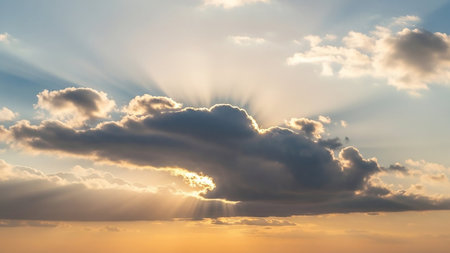 Rays showing sunbeams breaking through dark clouds illuminating the sky with golden light and soft orange hues at sunset keywords: sunbeams, crepuscular rays, light...の素材
