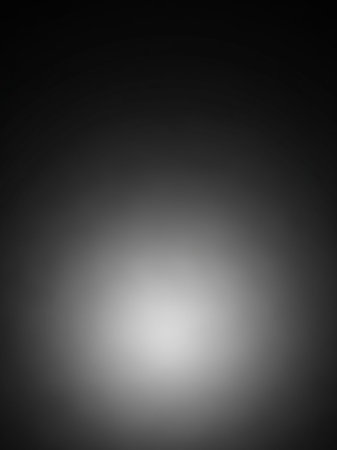 A soft white light glows from the center of a dark gray gradient background, creating a subtle halo effect with diffused shadows.の素材