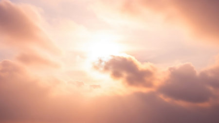 Soft peach and white clouds are illuminated by bright sunlight, creating a serene and ethereal sky panorama with diffused light.の素材