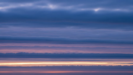 Dusk showing horizon line with layers of blue and purple clouds at dusk or dawn with a faint orange glow on the horizon. resolutionの素材