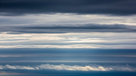 Horizontal bands of dark gray and white clouds stretch across the frame, with slivers of blue sky visible between them.の素材