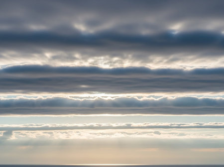 Dusk showing dramatic horizontal cloud layers illuminated by sunbeams over a calm ocean horizon at dawn or dusk. resolution use.の素材