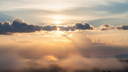 Golden sunbeams break through dramatic clouds and soft mist, illuminating a serene landscape of rolling hills and trees at sunrise.の素材