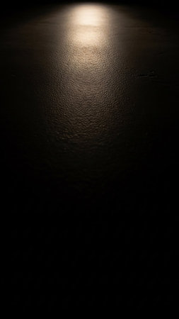 A bright light shines on a dark, textured surface, creating a dramatic spotlight effect that fades into blackness.の素材