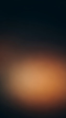 A soft abstract background a smooth gradient from deep dark blue to warm burnt orange and brown tones, illuminated by a gentle, subtle glow.の素材