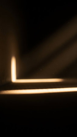 Abstract composition of geometric light beams and shadows creating distinct patterns on a dark background with a bright light source.の素材