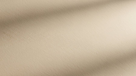 A close-up view of a textured beige surface with soft, diagonal shadows creating a subtle, abstract pattern and a clean backdrop.の素材