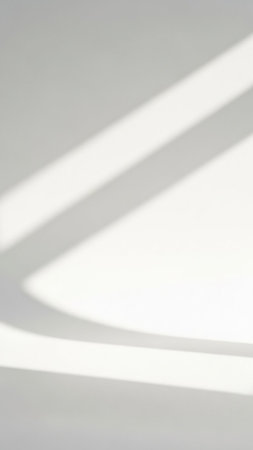 A clean white surface with soft diagonal light and shadow stripes forming abstract geometric shapes and lines.の素材