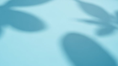 Simple showing soft blue background with blurred abstract plant leaf shadows creating a serene and minimalist aesthetic for projects keywords: blue, background,...の素材