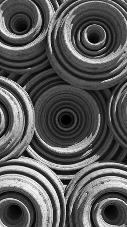 Black and white close-up of stacked circular with concentric rings and deep central holes, creating a textured, abstract, and visually complex pattern.の素材