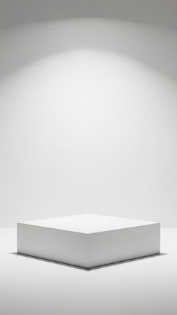 Stock showing a single white rectangular cube pedestal placed on a white studio floor with soft spotlight illumination and subtle shadows. resolutionの素材