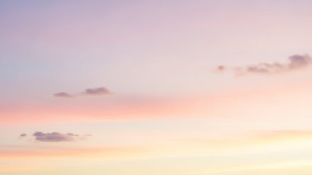 Subtle showing soft pastel gradient sky with subtle hues of pink, purple, and yellow, featuring a few small, wispy clouds scattered across the frame, creating a...の素材