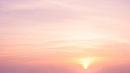 A soft pastel pink and purple sky with a gentle sun low on the horizon creates a serene and tranquil atmospheric background.の素材