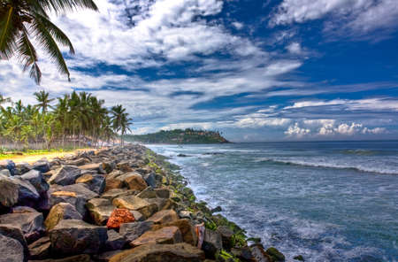 View of a rocky beach in kovalam and Leela on the hill top.の写真素材