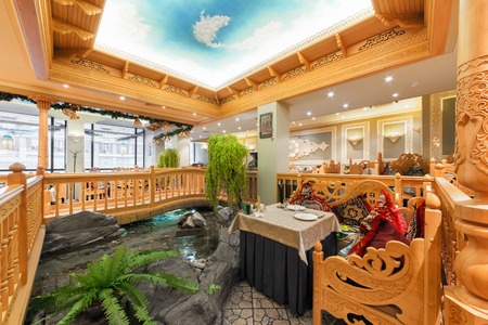 MOSCOW/RUSSIA - DECEMBER 2014. The interior of the deluxe restaurant of Uzbek cuisine - Babay Club in an oriental style. A table near the ornamental pond and a wooden bridgeのeditorial素材