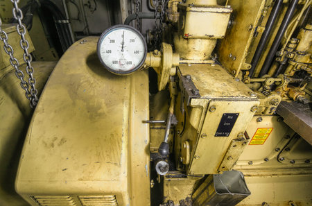 The ship's hold with yellow diesel engine mounted on ship. Engine room on a old cargo boat ship. The control panel with tachometerの写真素材