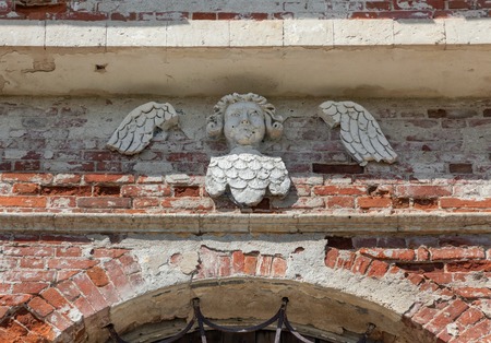 Decorative cherub on the brick wall of an abandoned templeの写真素材
