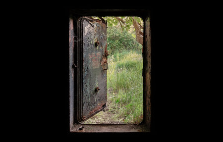Open the door of the old bunker. The view from the dark nature behind a door.