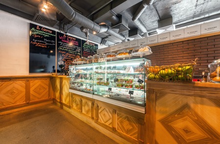 MOSCOW - AUGUST 2014: The interior gourmet cafe "IL GIORNO". Wooden cash register counter with glass showcase with desserts on the background menu coffee shopのeditorial素材