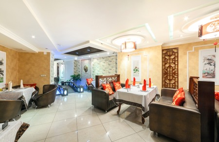 MOSCOW - AUGUST 2014: Interior of Chinese cuisine restaurant "HARBIN" in the traditional style. Lounge with tables and leather couches with red pillows with Chinese charactersのeditorial素材