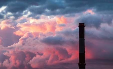 Industrial chimney stack silhouette against the background of the storm sky at sunsetの写真素材