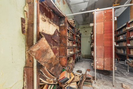 Bookcase with fallen off shelves and rotten books in an abandoned libraryの写真素材
