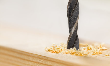 Metal drill bit make holes in a wooden plankの写真素材