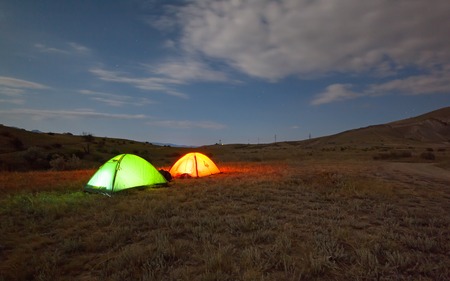 Green and red tent under the night sky in nature. The concept of traveling with tentsの写真素材