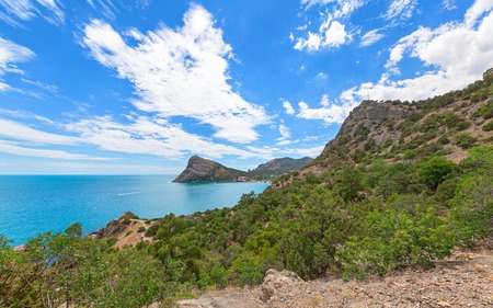 View of the Bay to the resort village near the mountains and with a large headland in the sea. Cape Chyken Peninsula of Crimea, resort Noviy Svetの写真素材