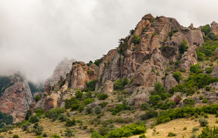 Clouds passing below the top of the mountain. Rocks of unusual shape. The strange cluster of rocks formed under the influence of wind and rain, at dawn. Ghost valley Crimea.の写真素材