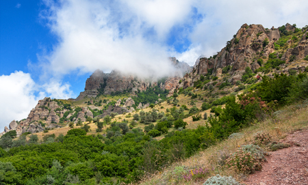 The slope of the mountain is overgrown with bushes, with a peak hidden behind clouds. Ghost valley Crimea.の写真素材