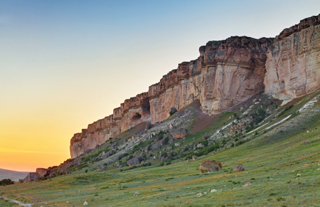 Vertical rocky wall at sunset with large boulders at the foot. Rock Aq Kaya, Crimeaの写真素材