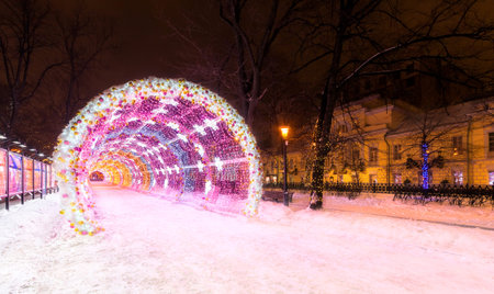 Entrance to the glowing decorative tunnel decorated with Christmas-tree toys and Christmas and New Year's attributes. City park at night in the center of Moscowの写真素材