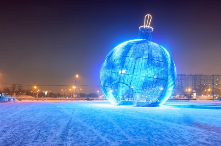 Giant glowing blue Christmas ball on the street with snowの写真素材