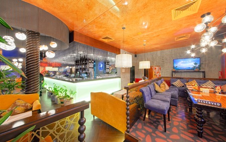 MOSCOW - SEPTEMBER 2014: The interior of the oriental restaurant "SANDYK". Chaikhana of Uzbek cuisine. Wooden table with blue corner sofa in the hallのeditorial素材