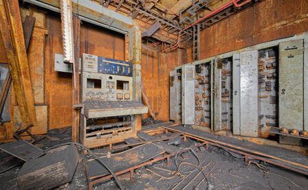 Old broken and covered with soot and rust control panel for power supply and cabinets for electrical equipment in abandoned after the fire industrial laboratoryの写真素材