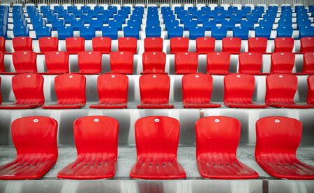 Empty red and blue rows of plastic seats in the stands of the stadiumの写真素材