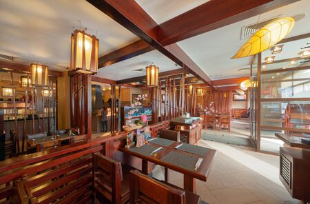 MOSCOW - SEPTEMBER 2014: The interior of the popular Japanese chain of restaurants "YAKITORIYA" in Moscow. Hall without visitors with wooden furniture. Modern design with traditional Japanese styleのeditorial素材