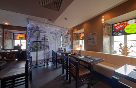 MOSCOW - SEPTEMBER 2014: The interior of the popular Japanese chain of restaurants "YAKITORIYA" in Moscow. Tables near the window with a long soft sofa Modern design with traditional Japanese styleのeditorial素材