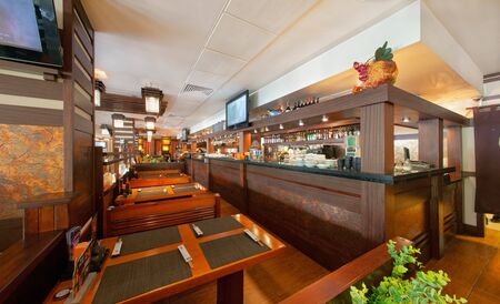 MOSCOW - SEPTEMBER 2014: The interior of the popular Japanese chain of restaurants "YAKITORIYA" in Moscow. Long bar counter near the tables for visitors. Modern design with traditional Japanese styleのeditorial素材